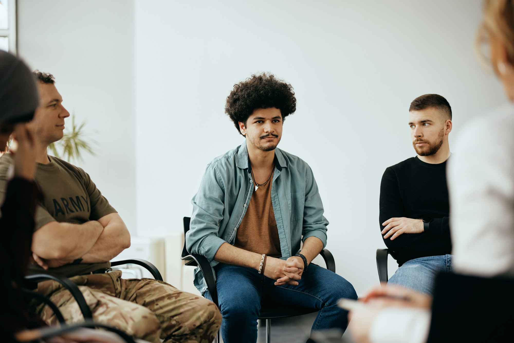 Young Muslim man attending group therapy at mental health center.